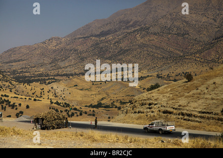 Un pick up car guida attraverso un checkpoint presidiati da combattenti curdi del Partito dei Lavoratori del Kurdistan o PKK al foothill del Quandil montagne, Iraq settentrionale Foto Stock