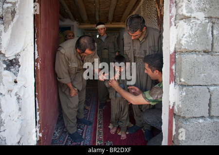 Combattenti curdi del popolo della Forze di Difesa HPG l ala militare del Partito dei Lavoratori del Kurdistan PKK guida un bambino in uniforme per contrassegnare il segno della vittoria nel Quandil montagne, vicino al confine iraniano nell Iraq del Nord Foto Stock