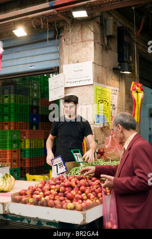 Un commerciante di un vegetale in stallo al Mahane Yehuda Market, Gerusalemme, Israele Foto Stock