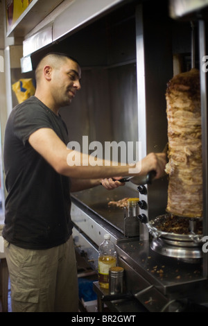Un uomo scolpisce le carni provenienti da un shawarma, re Shawarma Ristorante, Gerusalemme, Israele Foto Stock