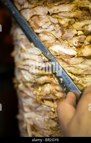Un uomo scolpisce le carni provenienti da un shawarma, re Shawarma Ristorante, Gerusalemme, Israele Foto Stock
