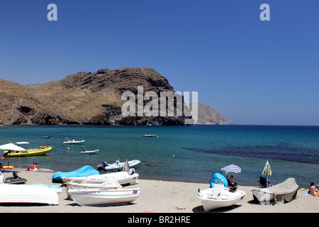 Vista panoramica della spiaggia di Las Negras, Andalusia Spagna mostra barche da pesca sulla sabbia; roccioso promontorio in background Foto Stock