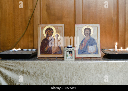 Icone Religiose della Madonna con il bambino e Gesù Cristo con candele su una tabella in una chiesa ortodossa greca. Foto Stock