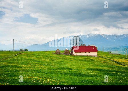 Paesaggio con una casa su una prateria sotto il cielo con le nuvole Foto Stock