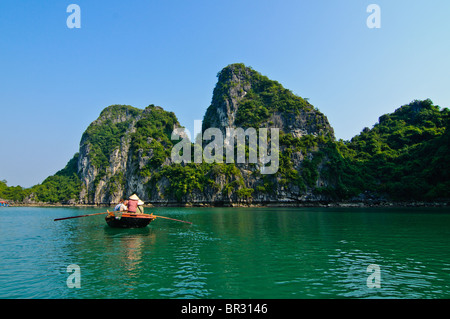 Il vietnamita e alcuni turisti in una barca al di fuori di un villaggio di pescatori che si trova nella baia di Halong, Vietnam Foto Stock
