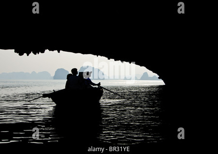 Silhouette di una barca con la gente nella baia di Halong, Vietnam Foto Stock