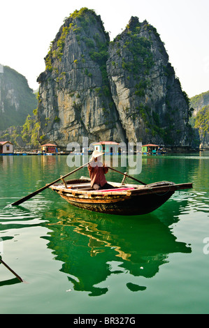 Vietnamita in una barca al di fuori di un villaggio di pescatori che si trova nella baia di Halong, Vietnam Foto Stock