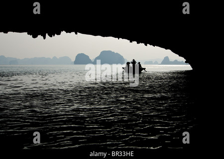 Silhouette di una barca con la gente nella baia di Halong, Vietnam Foto Stock