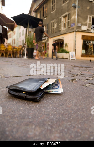 Perso il portafogli contenenti Euro / valuta europea note e mostra banca britannica e carte di credito, giacente su una strada basolata in Francia. Foto Stock