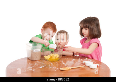 Tre simpatici ragazzi preschooler dosare gli ingredienti per la cottura in cucina. Isolato su bianco. Foto Stock