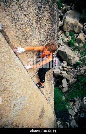 Angolo alto prospettica di una femmina di scalatore lavorando su una spaccatura su un muro di granito. Foto Stock