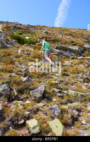 Poco carino boy in salita su una montagna Foto Stock