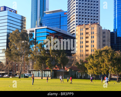 Gli impiegati a giocare a calcio in pausa pranzo in un parco vicino alla città. Foto Stock