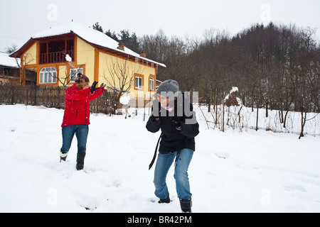 Due giovani donne a giocare nella neve con snowballs Foto Stock