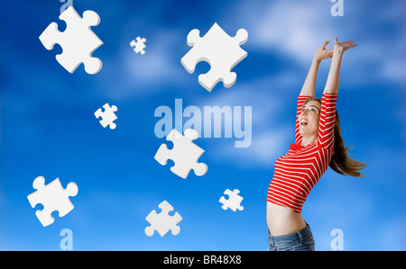 Bella donna felice con le soluzioni per i suoi problemi - Concetto con 3d i pezzi del puzzle fluttuante nel cielo Foto Stock