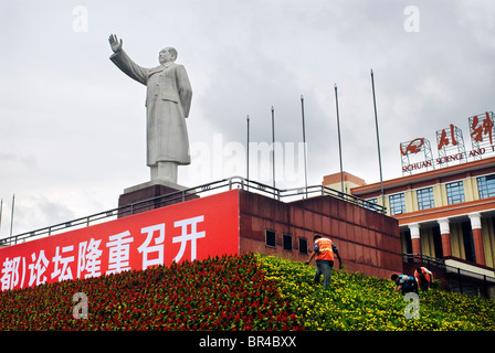 Una statua di Mao Tse Tung torri rispetto ai lavoratori il mantenimento di fiori alla sua base a Chengdu nella provincia di Sichuan, in Cina. Foto Stock