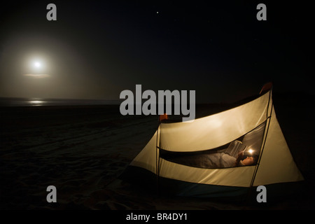 Uomo caucasico camping sulla spiaggia Foto Stock