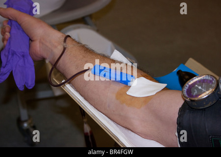 L uomo dà la donazione di sangue con ago nel suo braccio Foto Stock