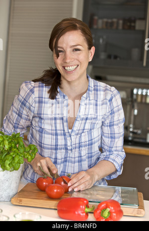 La donna per affettare i pomodori in cucina Foto Stock