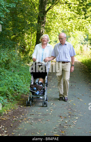 I nonni di andare a fare una passeggiata al nipote in passeggino Foto Stock