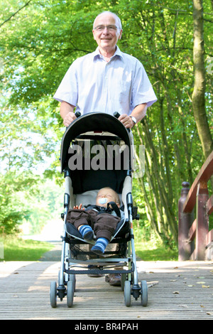 Il nonno di andare a fare una passeggiata al nipote in passeggino Foto Stock