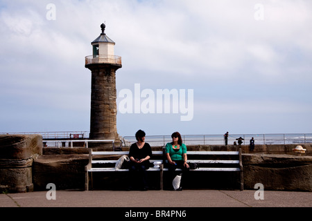 Due donne in appoggio su un molo vecchio a Whitby, North Yorkshire, Inghilterra. Foto Stock