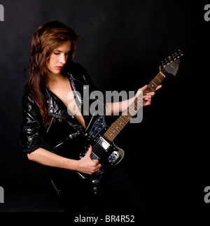 Ragazza giovane con la chitarra su sfondo nero Foto Stock