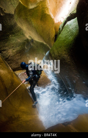 L'uomo rappelling giù canyon attraverso la cascata in Utah. Foto Stock