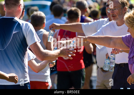 Piccole bottiglie di plastica di Buxton ancora acqua minerale di essere consegnati ai concorrenti nella maratona di Nottingham Foto Stock