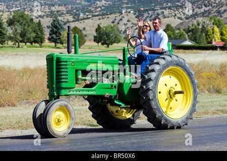 Sposa coppia sposata a cavallo sul trattore di antiquariato in loro nozze processione dalla chiesa al ricevimento, Salida, Colorado Foto Stock