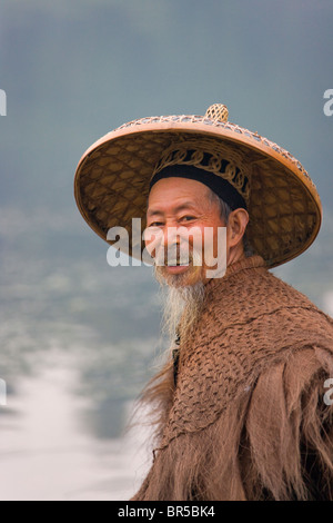 Fisherman indossando cappotto di paglia sul Fiume Li e Yangshuo, Guangxi, Cina Foto Stock