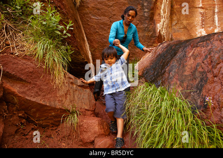 Madre aiutare figlio salire lungo le rocce Foto Stock