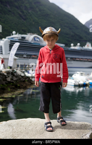 Ragazzo che indossa un casco Viking al porto di Geiranger, Norvegia con la nave da crociera Crown Princess ancorato in background Foto Stock