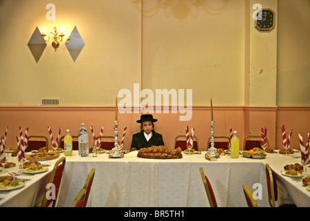 Un 13-anno vecchio ebreo ortodosso ragazzo si siede in attesa per il suo bar mitzvà per iniziare in un Parces hall, Stamford Hill. Foto Stock