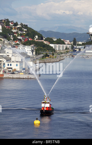 Fire rimorchiatore la spruzzatura di acqua come un send-off per nave da crociera Foto Stock