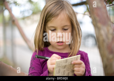 Bambina di cinque anni per imparare a scrivere le lettere con carta e penna Foto Stock