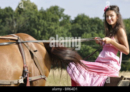 Bella giovane donna a cavallo di un vecchio carrello Foto Stock