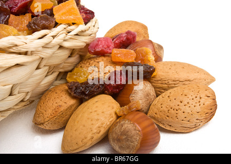 Frutti essiccati misti e i dadi fuoriuscita dal cesto su sfondo bianco. Foto Stock