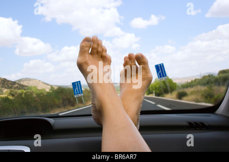 Piedi appoggiati sul cruscotto di automobile Foto Stock