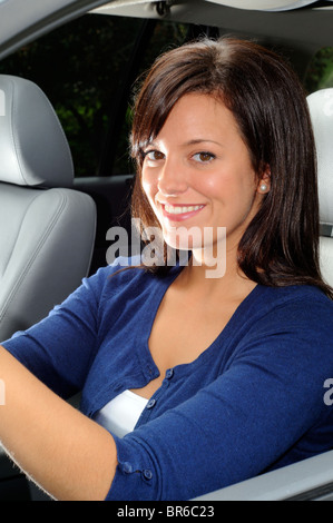 Attraente giovane donna Conducente seduto nel sedile del guidatore della sua automobile Foto Stock