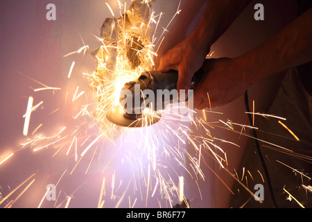 Tagli idraulico attraverso il tubo di metallo con sega radiale facendo scintille di colore arancione Foto Stock