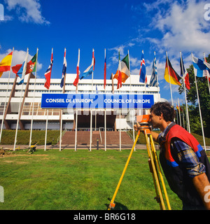 Geometra prendendo le misure con un teodolite nella parte anteriore del consiglio d'Europa edificio, Strasburgo, Alsazia, Francia Foto Stock