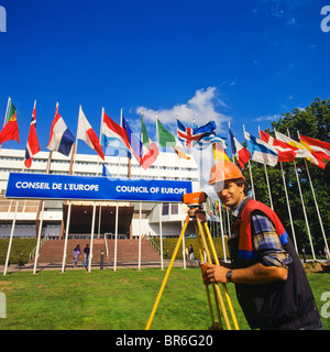 Geometra prendendo le misure con un teodolite nella parte anteriore del consiglio d'Europa edificio, Strasburgo, Alsazia, Francia Foto Stock