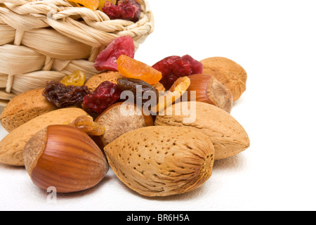 Frutti essiccati misti e i dadi fuoriuscita dal cesto su sfondo bianco. Foto Stock