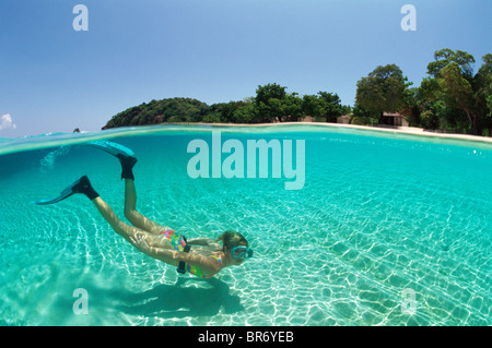 A livello diviso colpo di snorkler nuoto in chiaro acque poco profonde su sabbia, Malaysia. Foto Stock