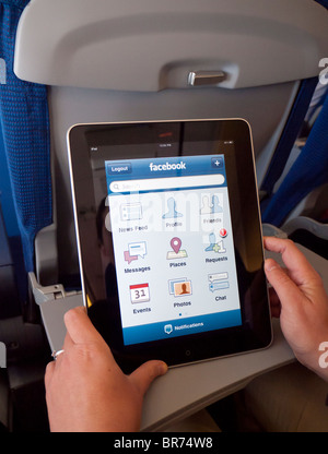 Donna che utilizza iPad computer tablet per controllare Facebook quando vola su jet del passeggero Foto Stock