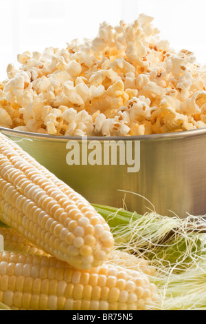 Spighe fresche di mais e una ciotola di pop-corn Foto Stock