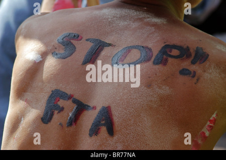 Un uomo con uno slogan sulla sua schiena prende parte a una manifestazione che si oppone a una proposta bilaterale USA-Tailandia accordo commerciale Foto Stock