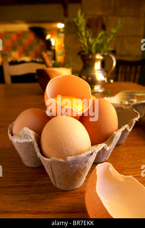 Free range uova, uno incrinato con un giogo, in una nazione impostazione di cucina Foto Stock