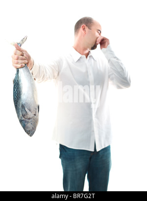 Giovane uomo tenere un puzzolente pesce in sua mano il fuoco selettivo